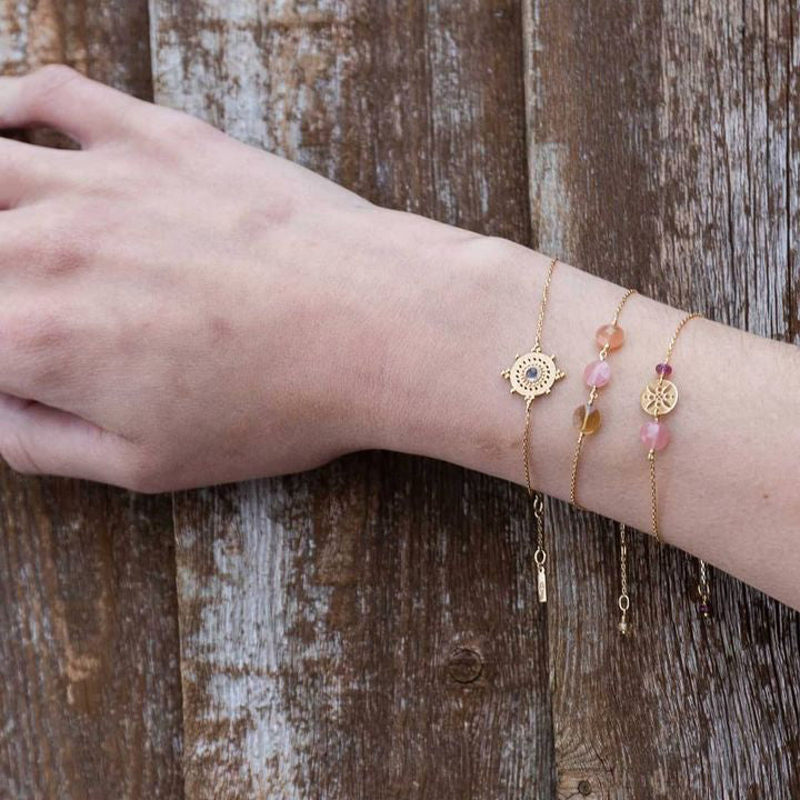 a wrist with 3 bracelets, central one is A gold chain bracelet with a trio of gemstones : Orange moonstone, pink Guava Quartz and Amber citrine, by Perle de Lune