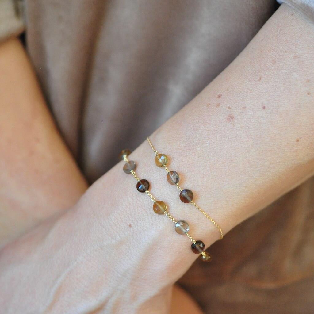 2 warm colours bracelets in 18k gold bracelet with luminous gemstones of golden colour Citrine and shades of Smoky Quartz all around the wrist of a model.