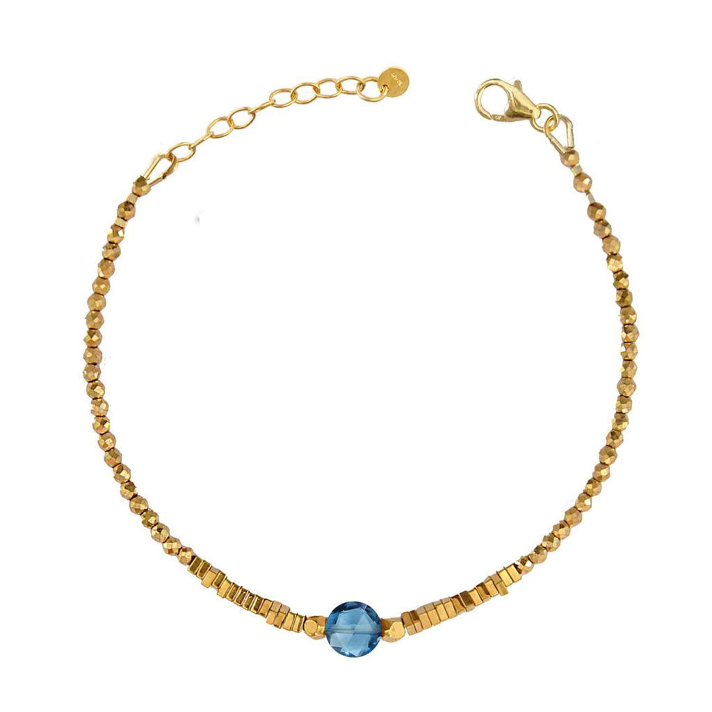 Elegant Hematite Beaded bracelet with a central faceted blue topaz gemstone on a white background. Perle de Lune jewelry