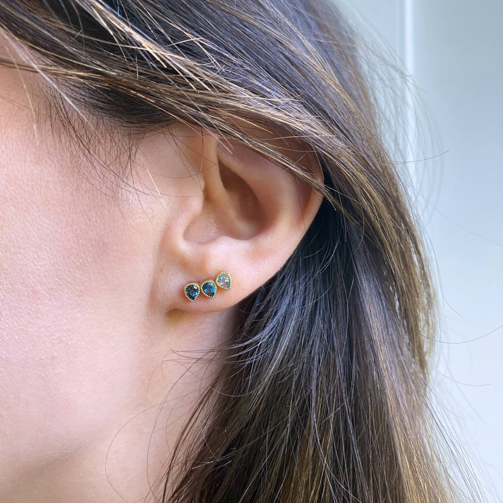 18k Yellow Gold Ear climber for left ear on a model with 3 gemstones of Blue topaz in gradient shades of Swiss blue topaz and London blue topaz