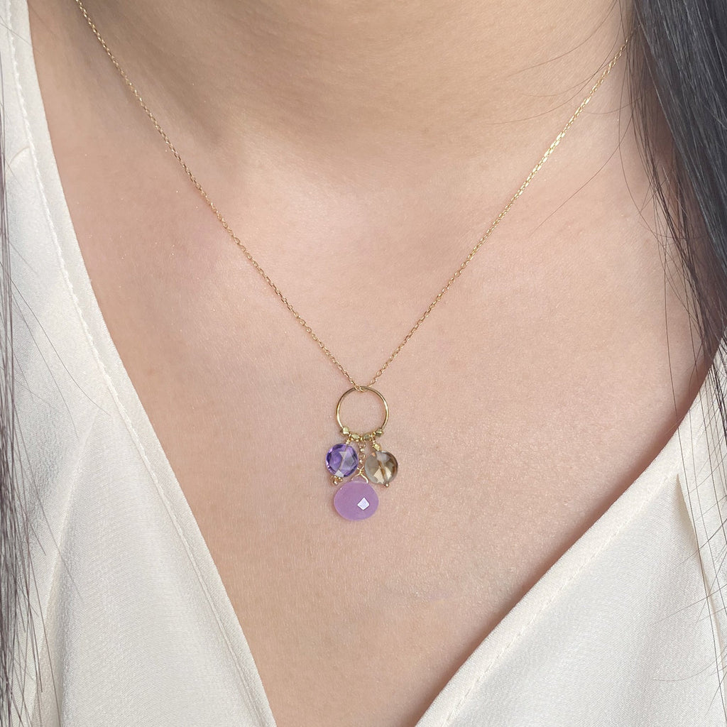 A 18k chain with a charm with 3 gemstones of Amethyst, Lavender Jade & Smoky Quartz Hanging on a ring displayed on a model neck