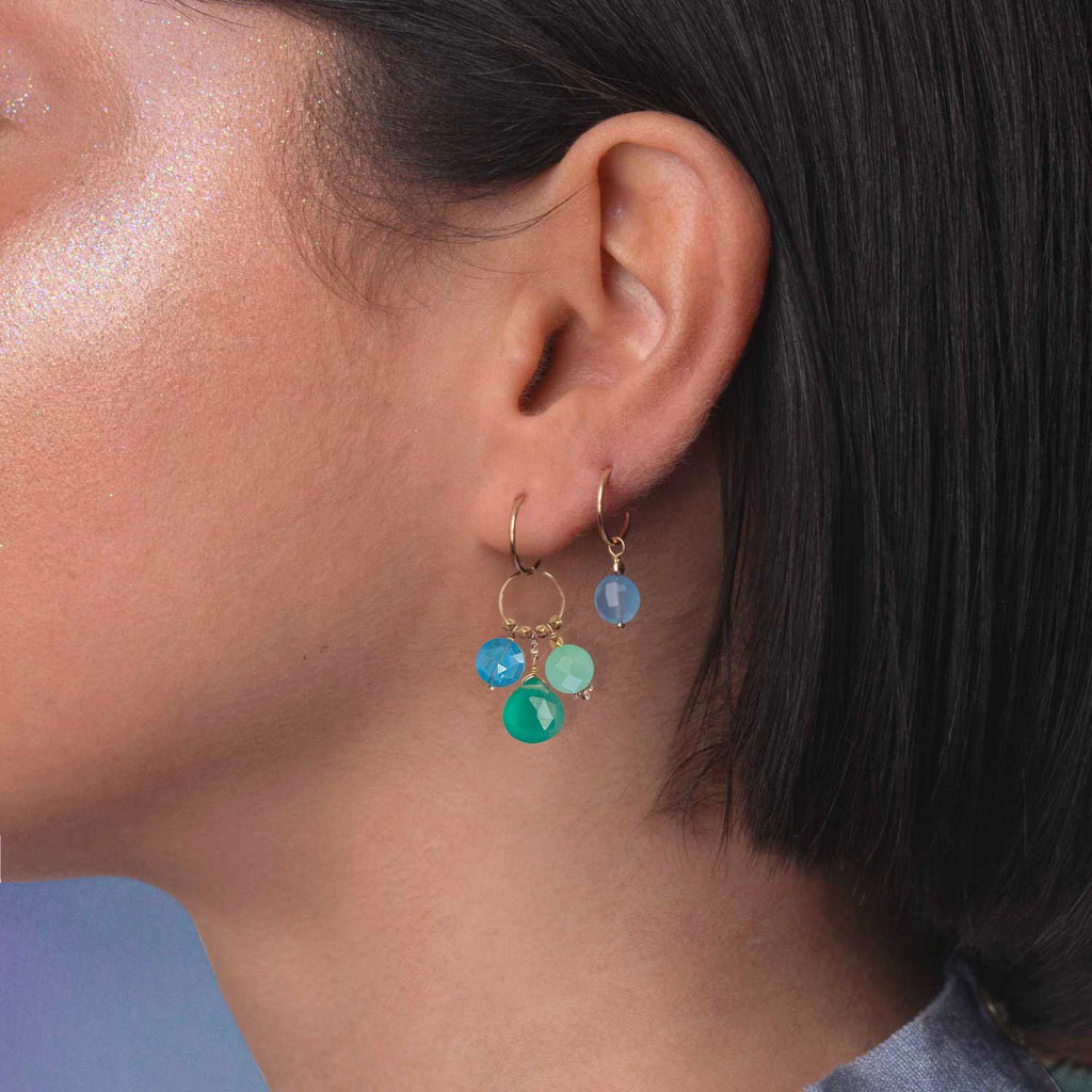 A gemstone charm in 18k gold with a trio of of Apatite, Green Agate and Chrysoprase  on a model ear 