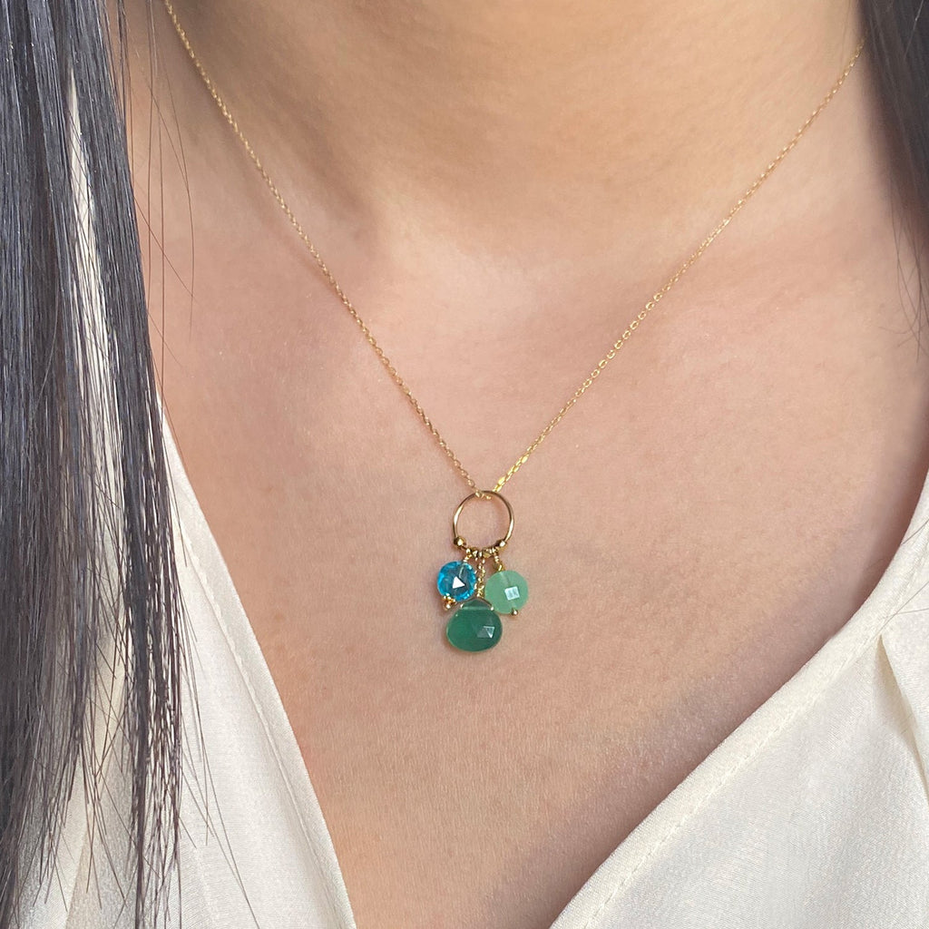 A 18k chain with a charm with 3 gemstones of Apatite, Green Agate and Chrysoprase hanging on a ring displayed on a model neck