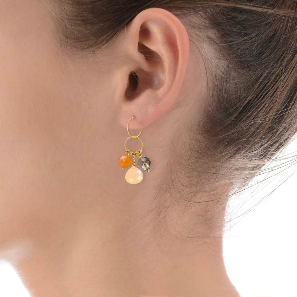 A gemstone charm in 18k gold with a trio of of Carnelian, Orange Jade and  Smoky Quartz  on a model ear 