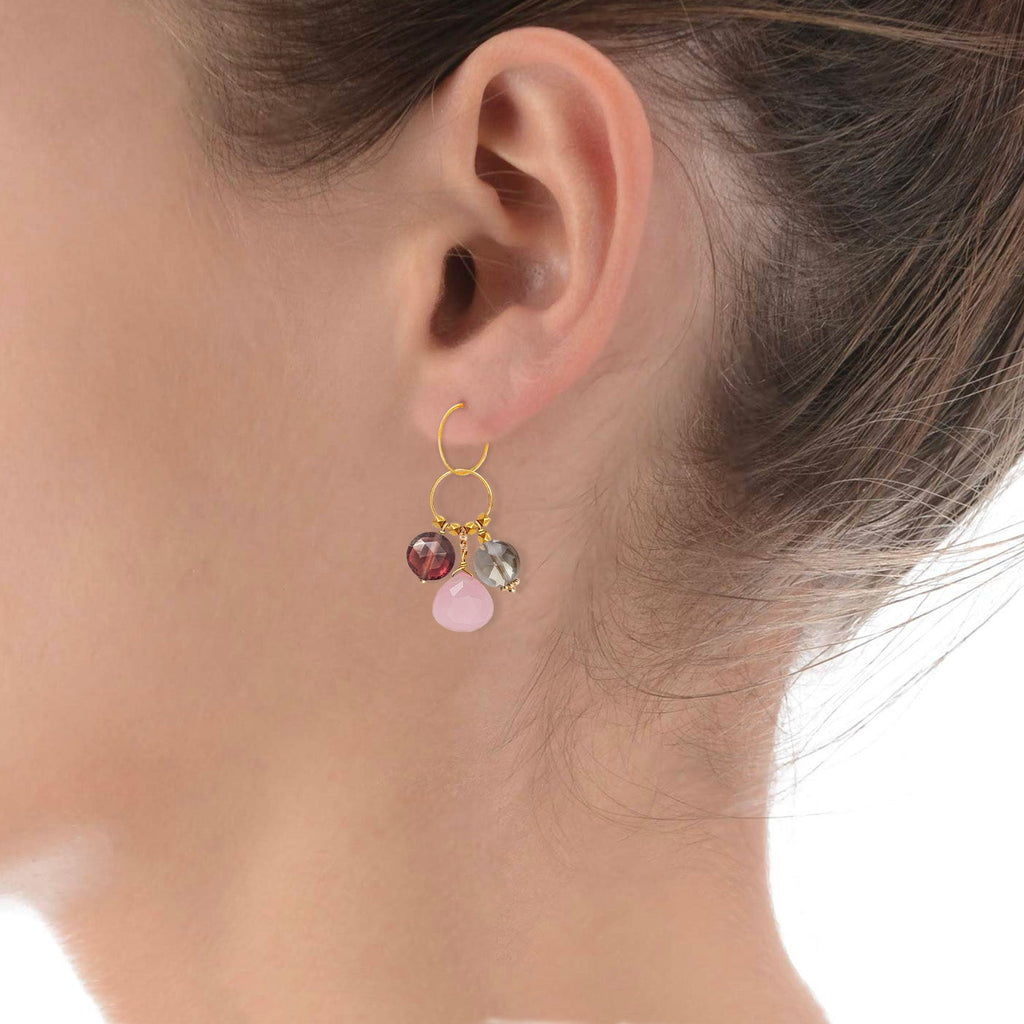 A gemstone charm in 18k gold with a trio of of Garnet, Guava Quartz & Smoky Quartz on a model ear 